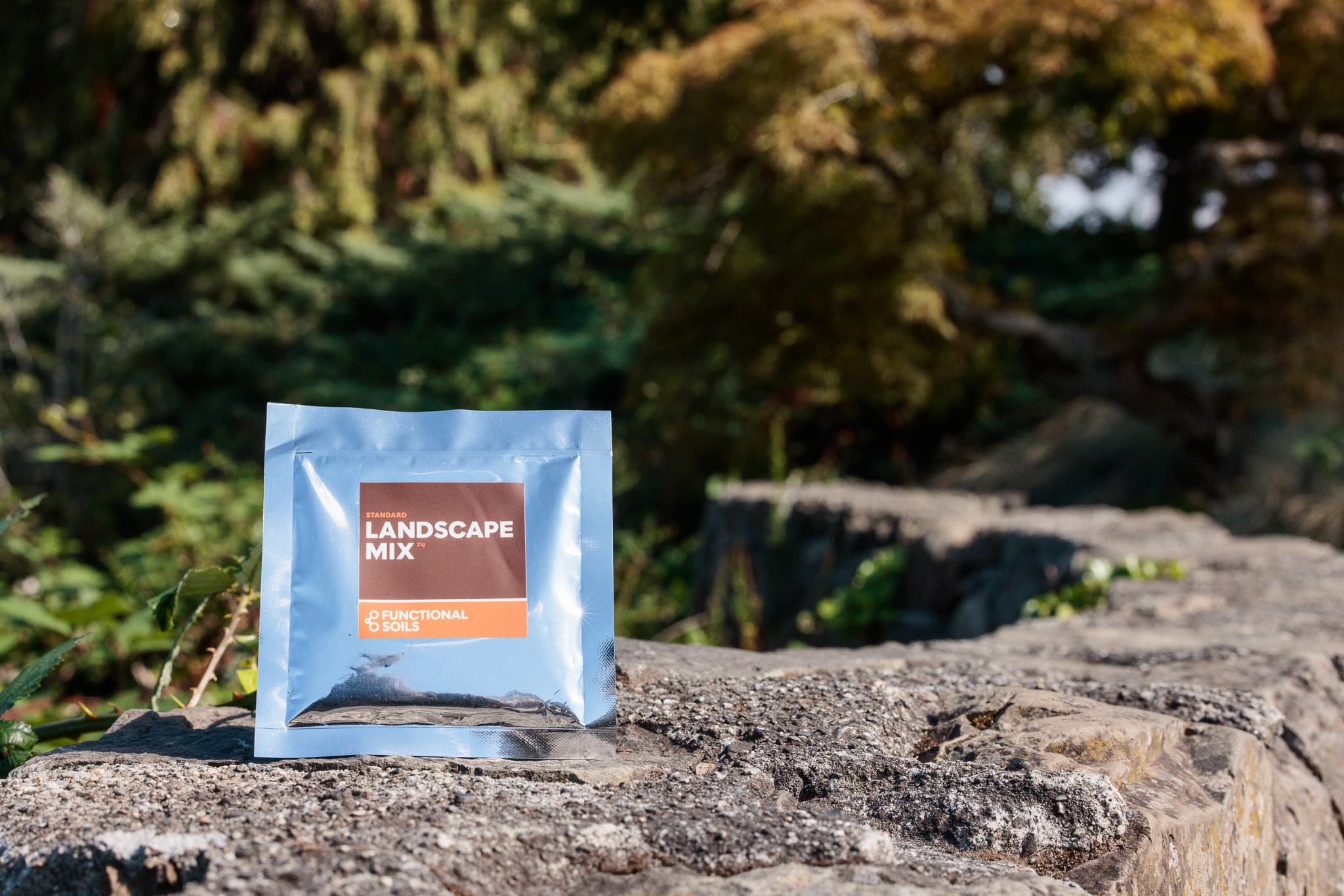 A Landscape Mix pouch standing on a stone garden wall